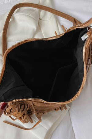 Caramel suede crescent crossbody bag with fringe detail and zip closure.