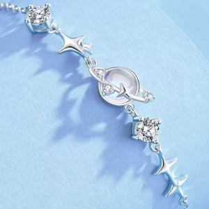 Silver celestial bracelet with stars, planet charm, and cubic zirconia accents.