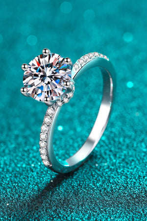 Silver moissanite ring with pavé band and six-prong setting.