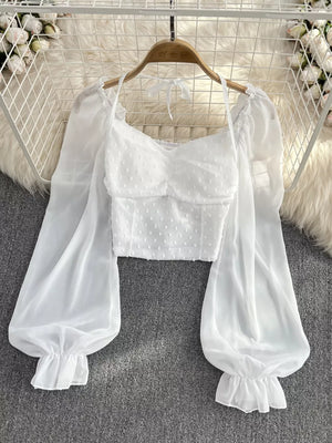 White Swiss dot maternity blouse with ruffled long sleeves and halter neckline.