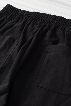 Black seamed front wide leg trousers with elastic waistband and patch pockets.
