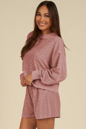 Dusty pink checkered textured lounge set with crew neck sweatshirt and shorts.