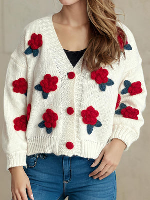 White knit cardigan with red rose appliqués and buttons, V-neck, long sleeves.