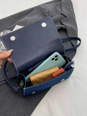 Artisanal mini denim crossbody bag in dark blue with white stitching, showing interior phone and wallet.