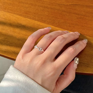 Sleek sterling silver ring with a chain-link geometric design on a woman's finger.