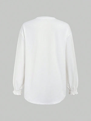 White oversized tunic top with ruffled cuffs and long sleeves.
