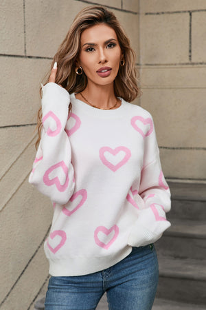 White acrylic knit sweater with pink heart intarsia pattern, crewneck, long sleeves.