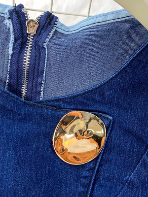 Dark blue denim vest with asymmetrical button and zipper detail.