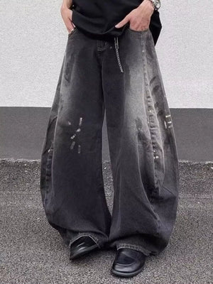 Men's black wide leg distressed jeans with a baggy fit and chain detail.