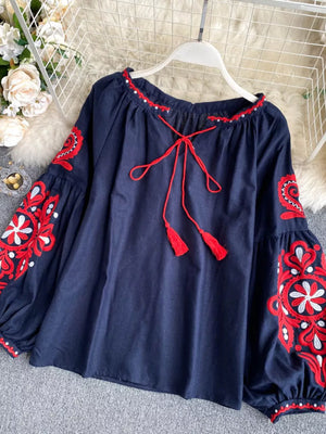 Navy blue peasant blouse with red embroidery, tie neck, and tassel details.