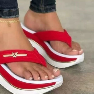Red platform wedge sandals with white sole detail and gold emblem.