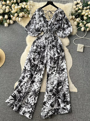 Tropical print smocked wide-leg romper with V-neck and puff sleeves.