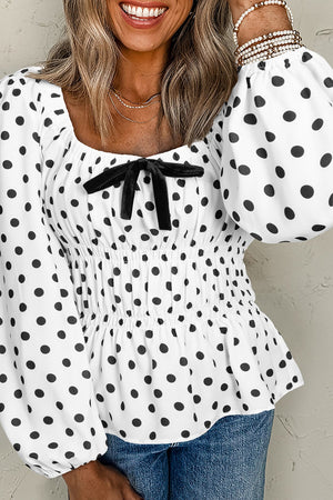 White polka dot blouse with smocked waist, puff sleeves, and black bow detail