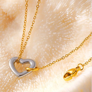 Gold chain bracelet with a two-tone heart charm and lobster clasp.