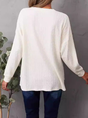 Ivory waffle knit henley shirt with long sleeves and side slits.