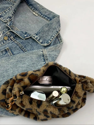 Leopard print faux fur shoulder bag with open zipper showing contents like a phone and makeup.