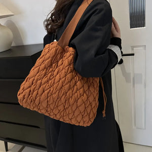 Quilted drawstring carryall bag in terracotta with a textured diamond pattern.