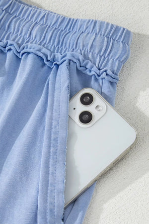 Light blue cotton drawstring shorts with pockets, showing a phone in the pocket.