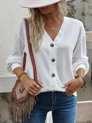 White waffle knit button-down cardigan with V-neck and brown buttons.