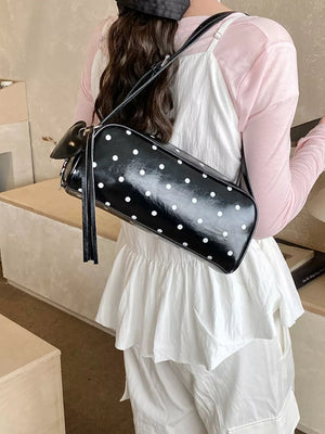 Black polka dot shoulder bag with adjustable strap and tassel detail
