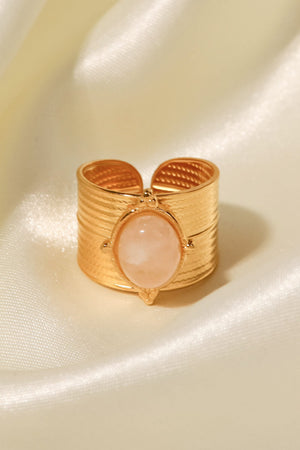 Gold cuff ring with textured band and oval peach stone accent