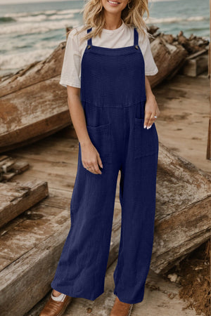 Dark blue textured cotton overalls with square pockets and wide legs, worn with a white t-shirt.