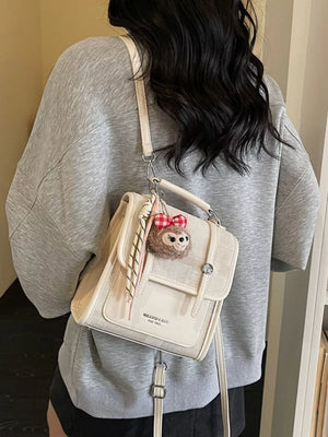 Chic mini flap backpack in white with plush charm and red bow.