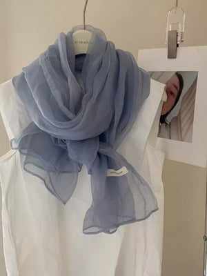 Light blue sheer polyester scarf with delicate texture, tied around a white top.