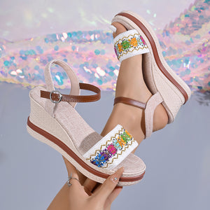 Embroidered floral wedge sandals in gray/white with adjustable strap and brown accents.