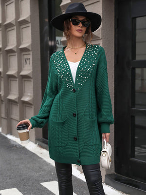 Green cable knit cardigan with pearl embellishments and pockets.