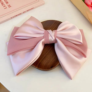 Blush pink satin bow barrette hair clip with sheer fabric overlay.