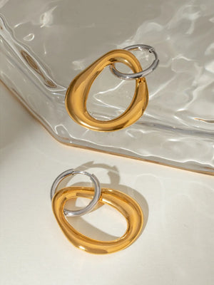 Two-tone sculptural asymmetric hoop earrings in gold, featuring a unique two-part design.