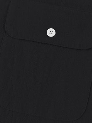 Black short sleeve henley shirt with textured fabric and a white button pocket detail.