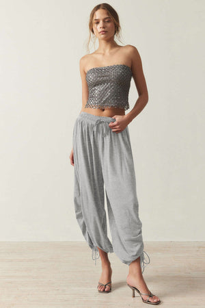 Gray balloon trousers with gathered ankle ties and drawstring waist.