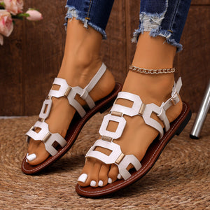 Sleek white cutout open-toe sandals with gold hardware and ankle strap.