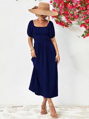 Dark blue midi dress with gathered bodice, square neckline, and puff sleeves.