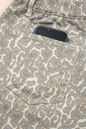 Denim shorts with leopard print and a back pocket holding a smartphone.