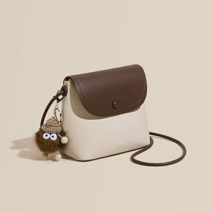 Mini pebbled pu leather crossbody bag in white and brown with a cute fuzzy charm.