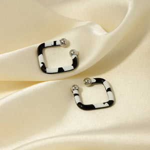 Geometric zebra stripe ear cuffs with silver ball details on a satin background.