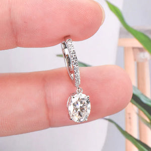 Silver pavé hoop and oval moissanite drop earrings with a detailed view of the stones.