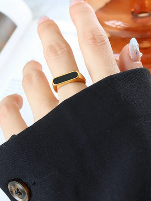 Gold rectangular signet ring with black enamel inlay detail.