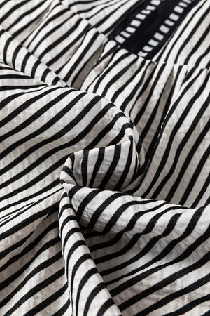 Chic black and white striped cotton tiered midi dress with pockets, close-up detail.