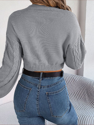 Cropped cable knit sweater in charcoal with mock neck and textured sleeves.