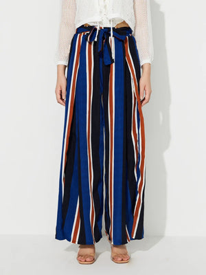 Striped palazzo trousers with side slits and a tie waist in blue, black, white, and rust stripes.