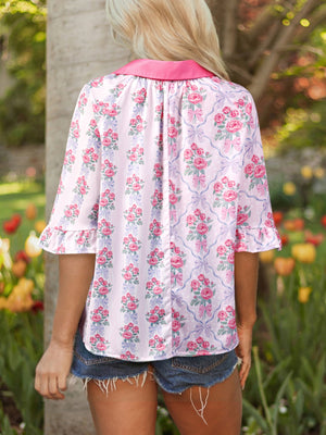 Maternity shirt with pink floral and bow pattern, ruffled sleeves, and pink collar.