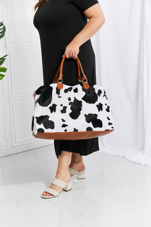 Cowhide print duffel bag with brown trim and handles
