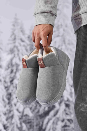 Gray suede shearling-lined house booties with brown 'M' logo tabs.