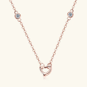 Rose gold necklace with linked heart pendant and two bezel-set clear accent stones.