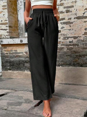 Black linen palazzo trousers with drawstring waist and wide legs.