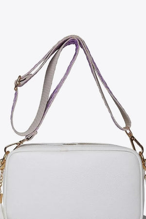 White textured crossbody bag with purple and gray striped strap and tassel detail